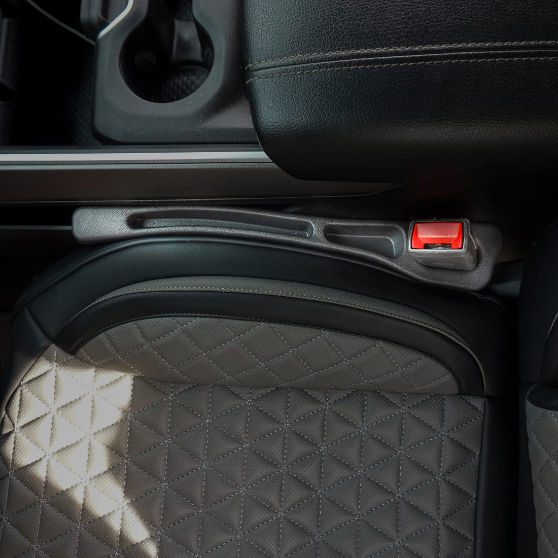 Close-up of a car seat with a red latch mechanism.