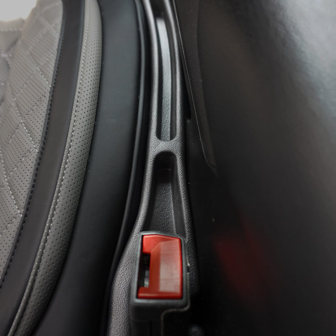 Close-up of a car seat with a red latch mechanism.