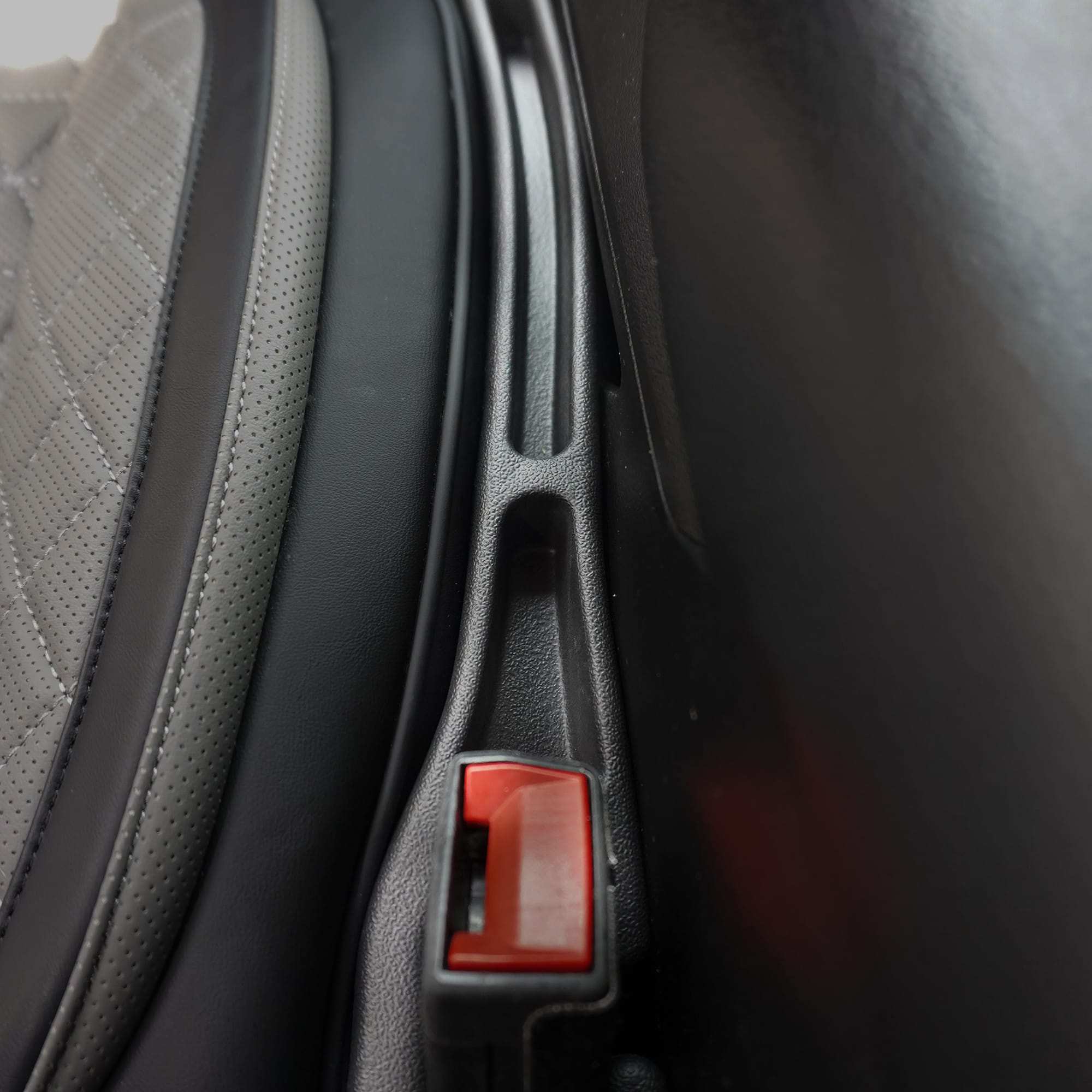 Close-up of a car seat with a red latch mechanism.